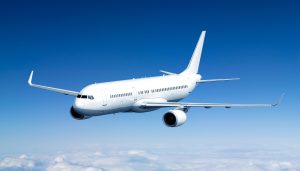Commercial aircraft flying above the clouds against a blue sky.
